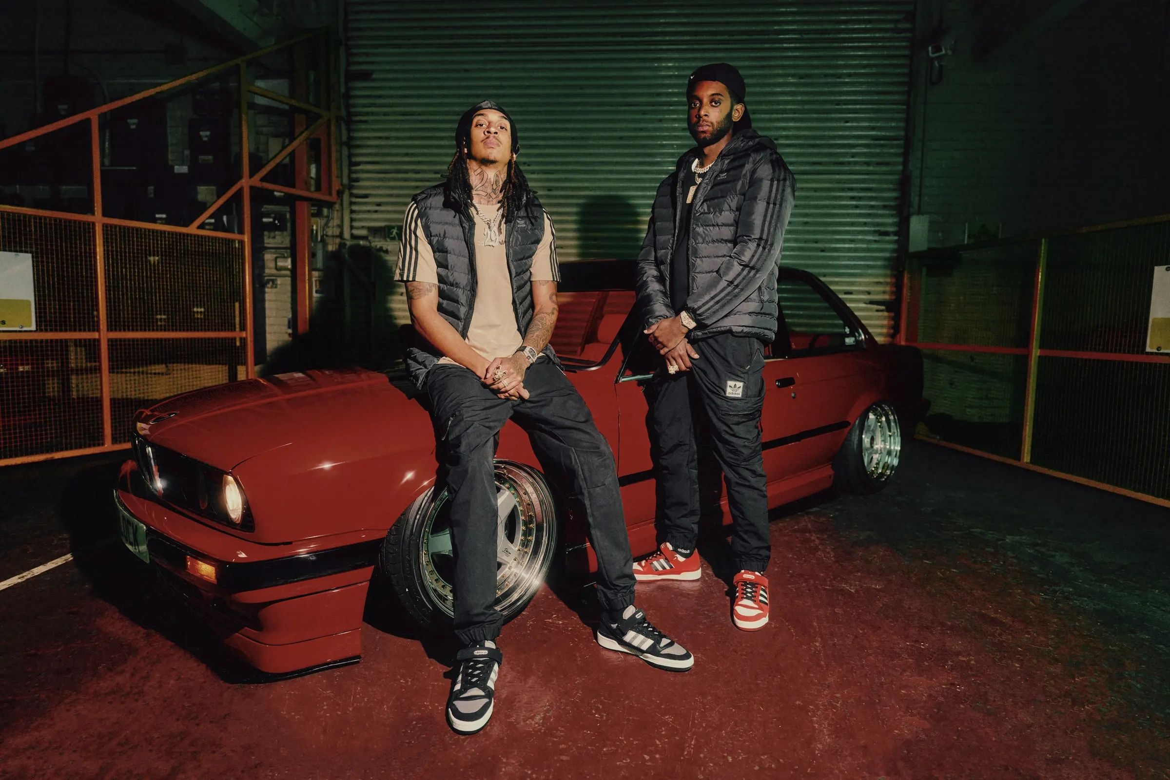 D-Block Europe sitting on a red classic BMW in a garage lined with roller shutters and orange cages