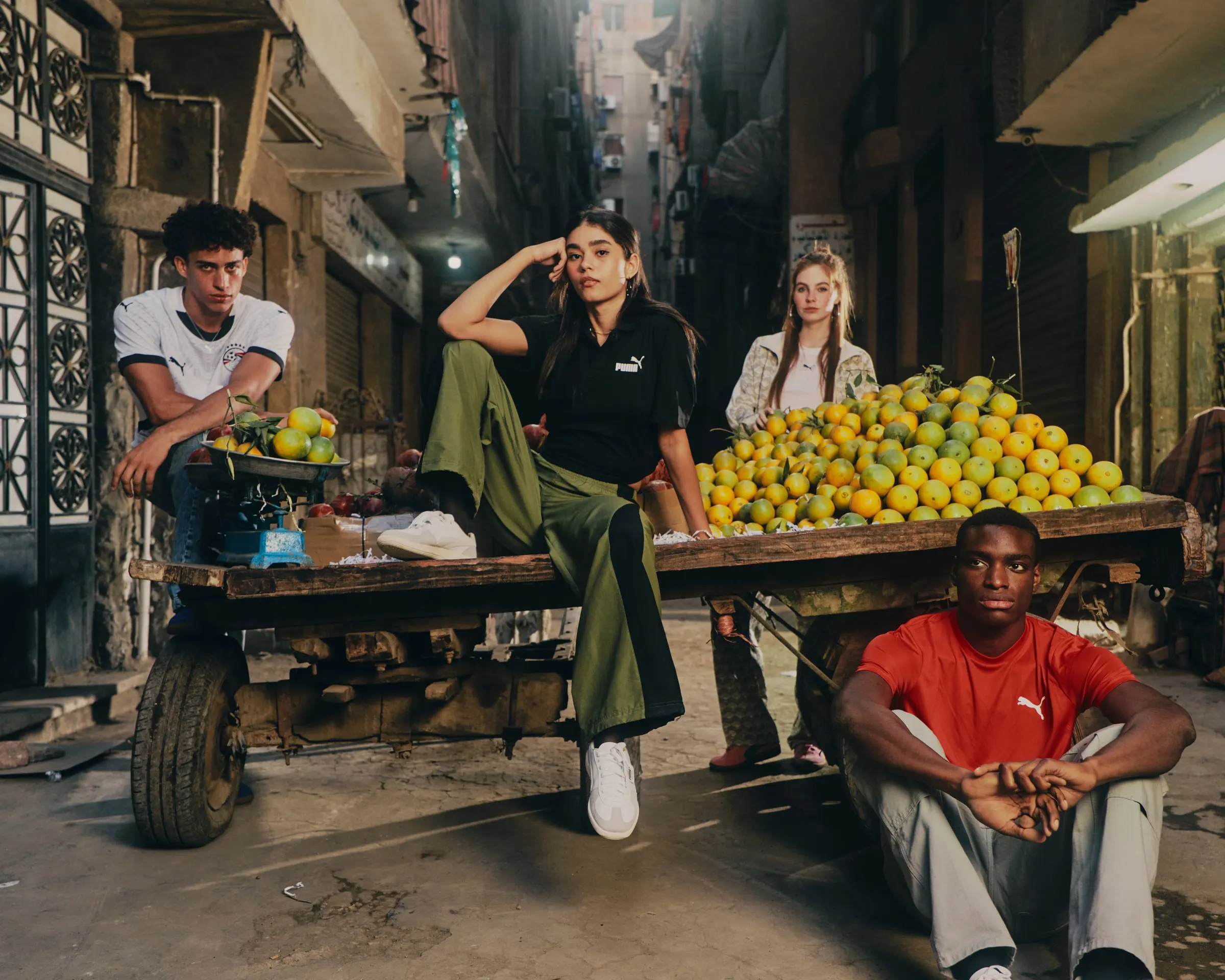Four friends in PUMA around a fruit cart in a narrow Cairo street