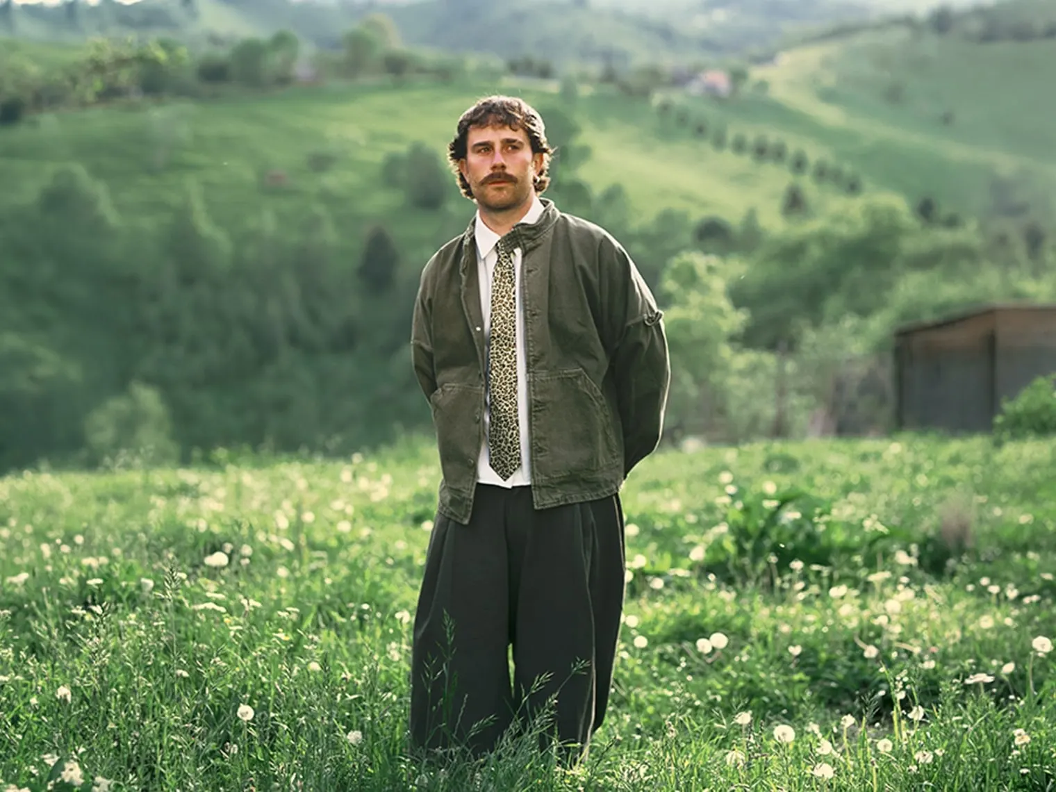 Sam Tompkins standing in a wildflower meadow, green hills behind
