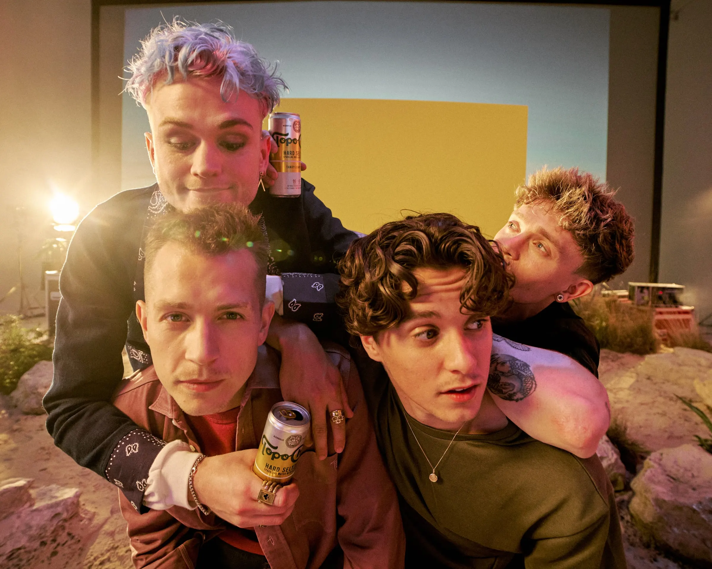 The band piled on top of each other, laughing, cans of Topo Chico in hand